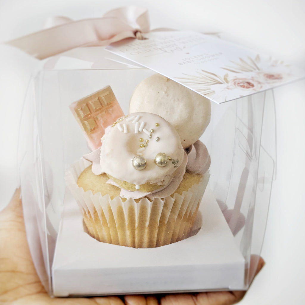Cupcake in a clear box held by a hand on a white background